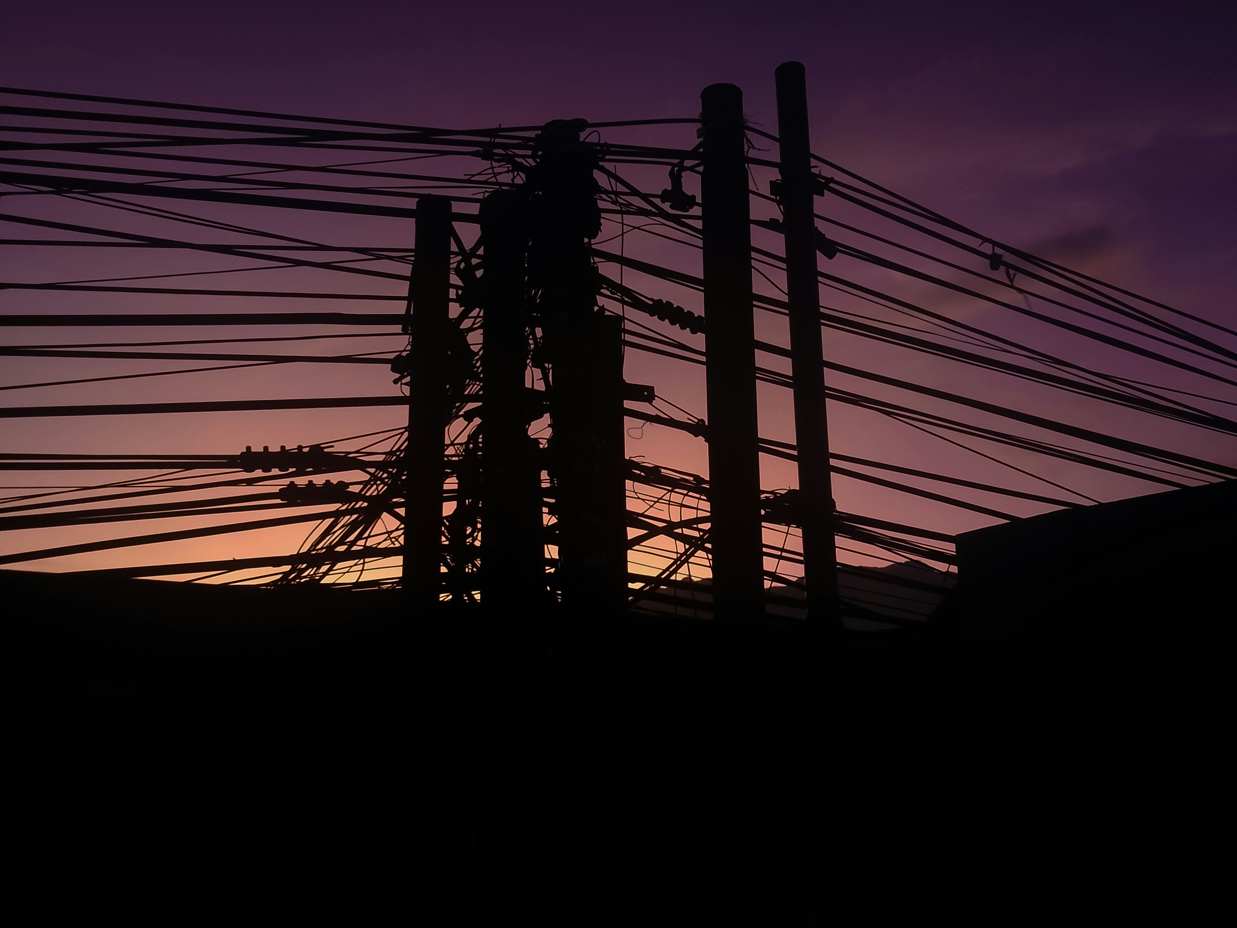 A group of electric poles silhouetted against the evening sky.