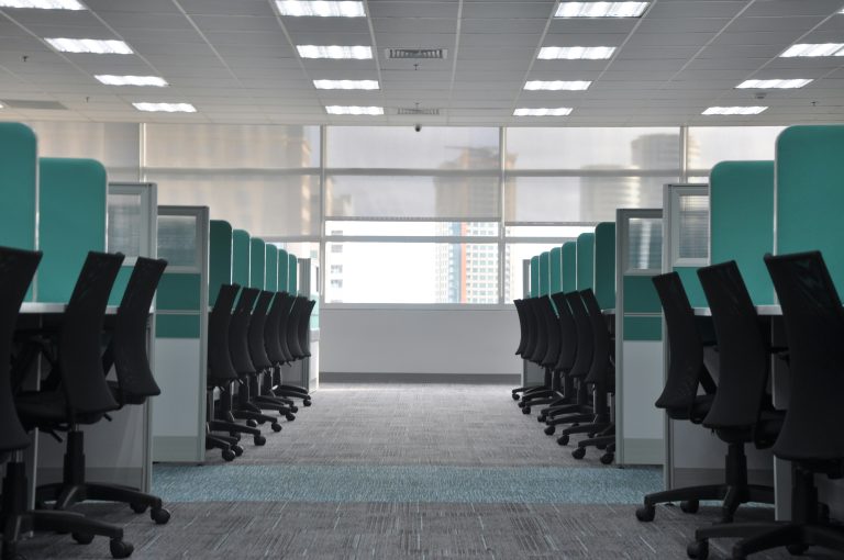 Empty black rolling chairs sit at office cubicles.