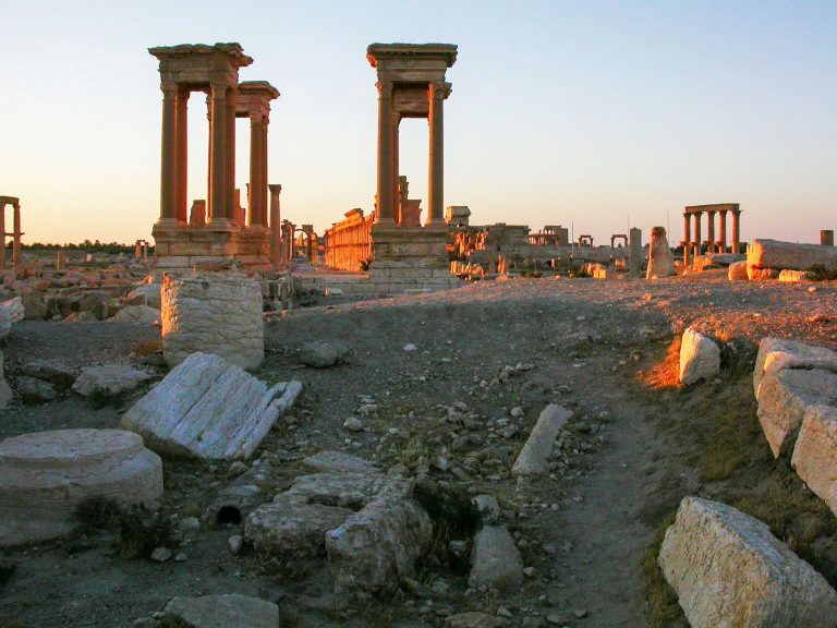 Ancient ruins of Palmyra bathed in warm sunlight, highlighting historic stone structures.