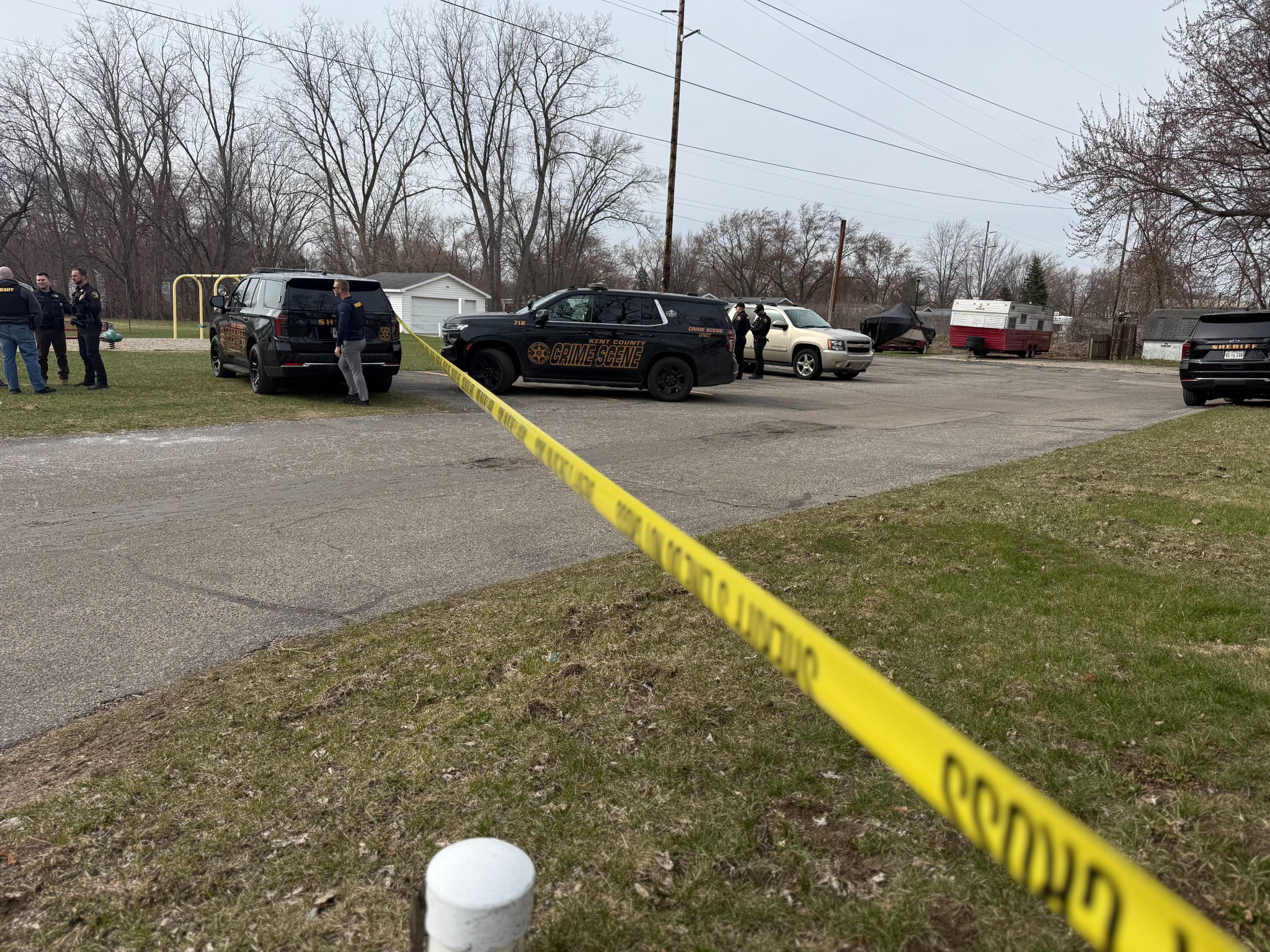 Kent County Sheriff's Office Crime Scene vehicles parked behind yellow police tape at Maplewood Mobile Home Park during an investigation into the deaths of a 38-year-old mother and 16-year-old daughter.
