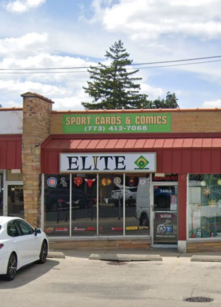 The exterior of Elite Sports Cards and Comics at 3406A N. Harlem Ave. featuring a green and white sign, red awning, and sports team logos in the windows.