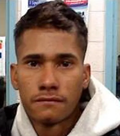 A close-up headshot of Jose Medina-Medina, a 25-year-old male with short dark hair and a light goatee, wearing a white hooded sweatshirt and a dark jacket against a light blue door frame.