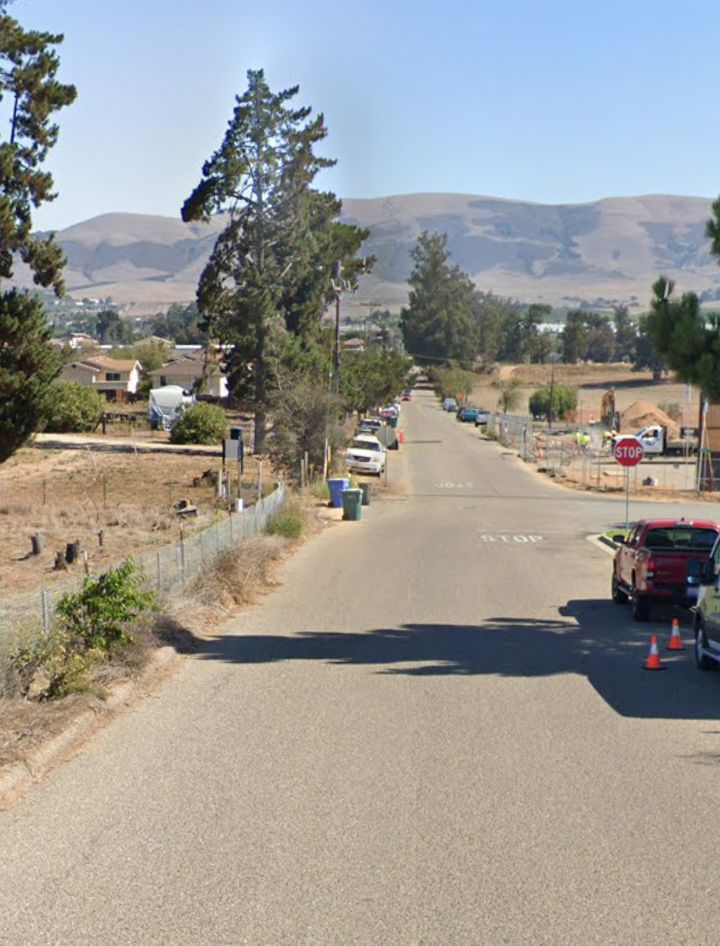 A street view of Hill Street in Nipomo, California, showing a residential area with hills in the background and a construction site on the right.