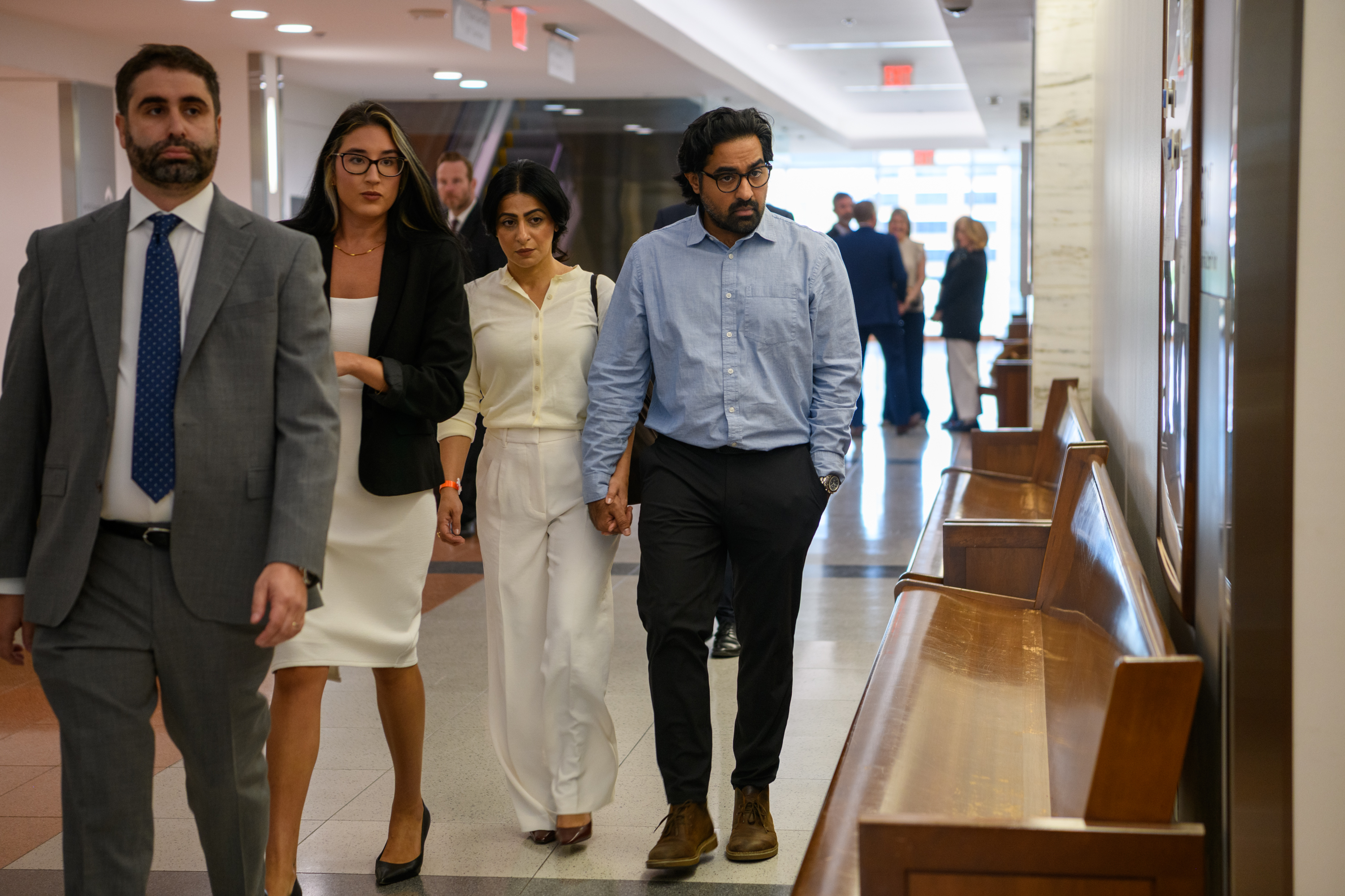 The biological parents, Nasheen Gilkar and Omar Ahmed, walk hand-in-hand through a sunlit corridor.